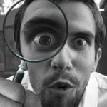 Una persona con una lupa observando algo detalladamente.