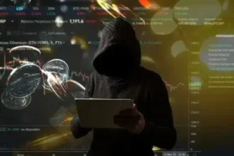 Usuario desconocido con gabardina negra utilizando una laptop.